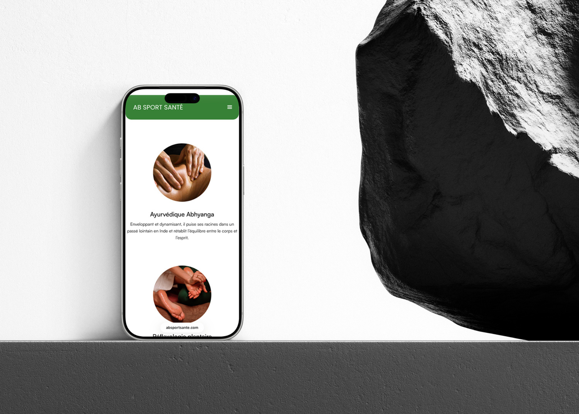 Smartphone affichant une page web d'AB SPORT SANTÉ avec images de massages ayurvédiques et réflexologie plantaire.