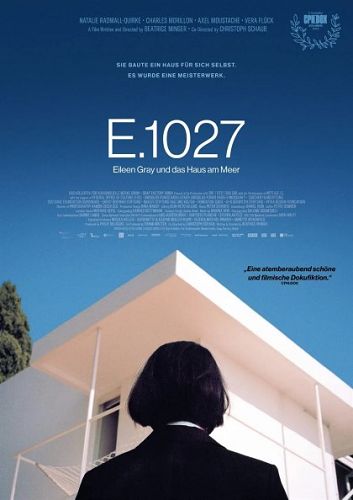 Filmposter von E.1027. Eine Frau steht vor einem modernen weißen Gebäude.