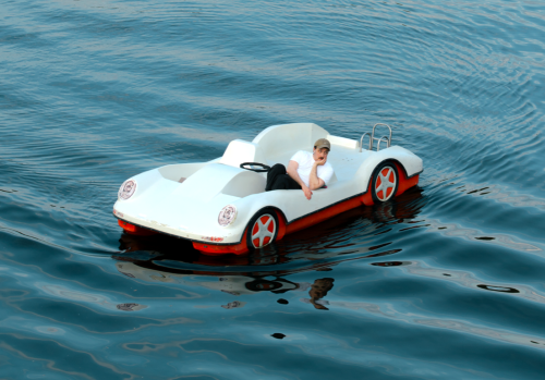 Fred Costea sitzt in einem Boot, welches die Form von einem Auto hat und von Wasser umgebenen ist.
