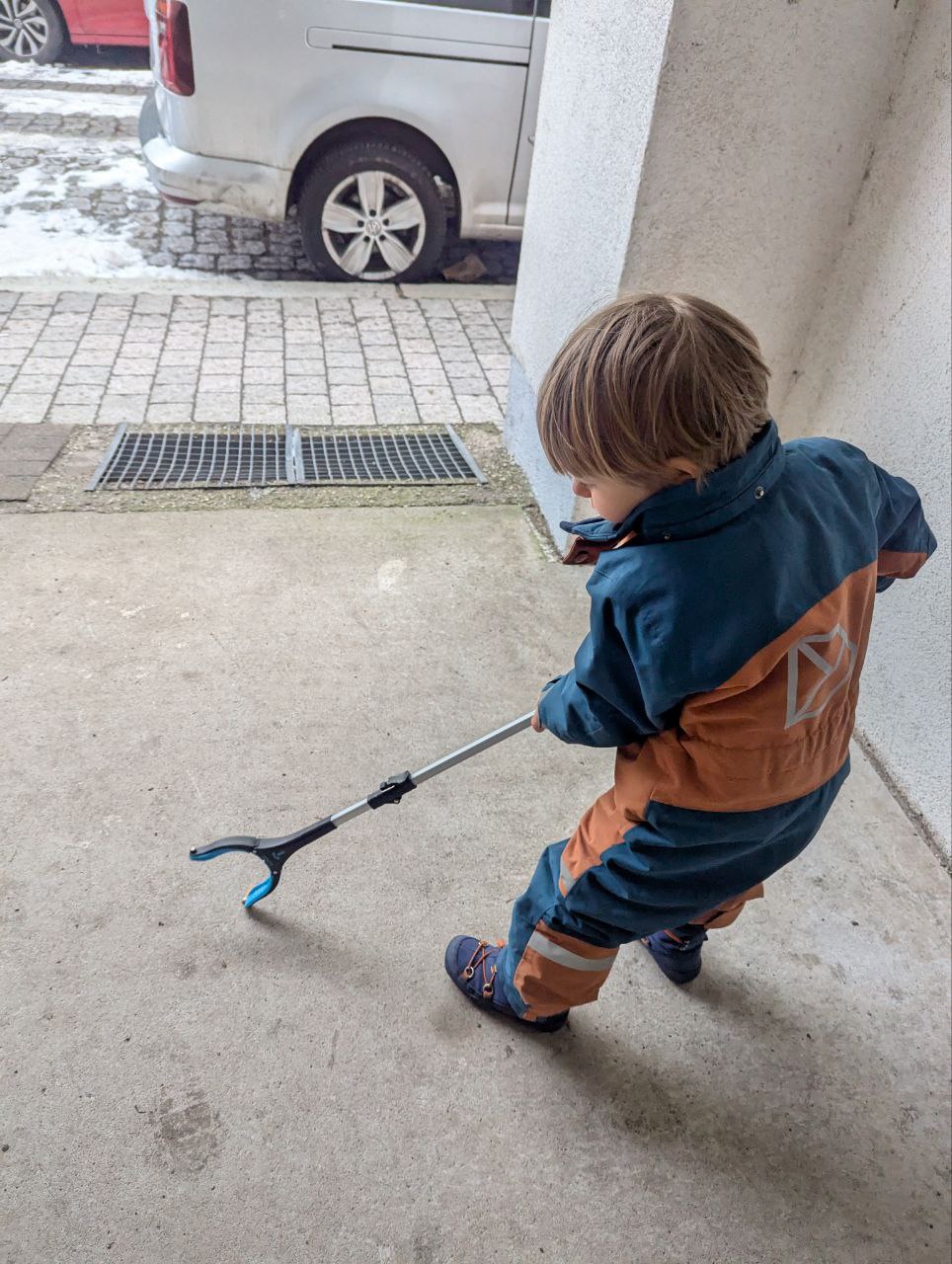 Zu sehen ist ein Kind mit einer Müllzange in der Hand