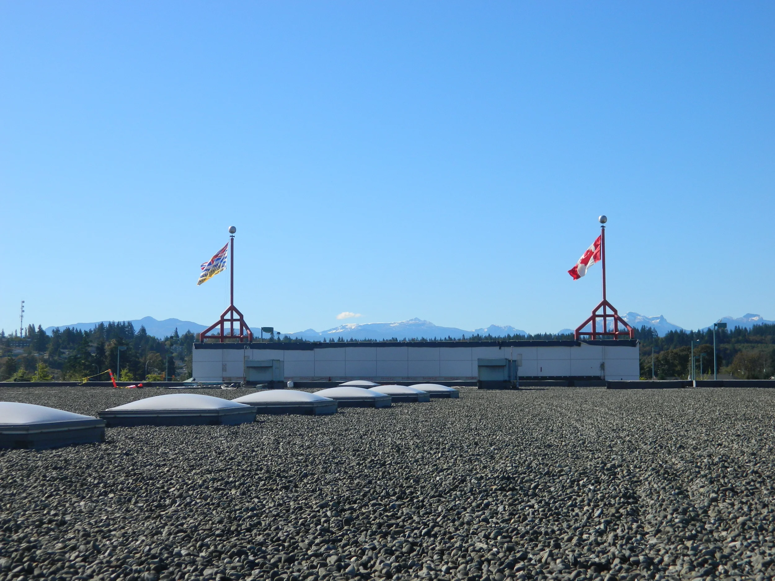 Nelson Roofing crew installing commercial membrane roofing and sheet metal cladding on a hospital campus on Vancouver Island