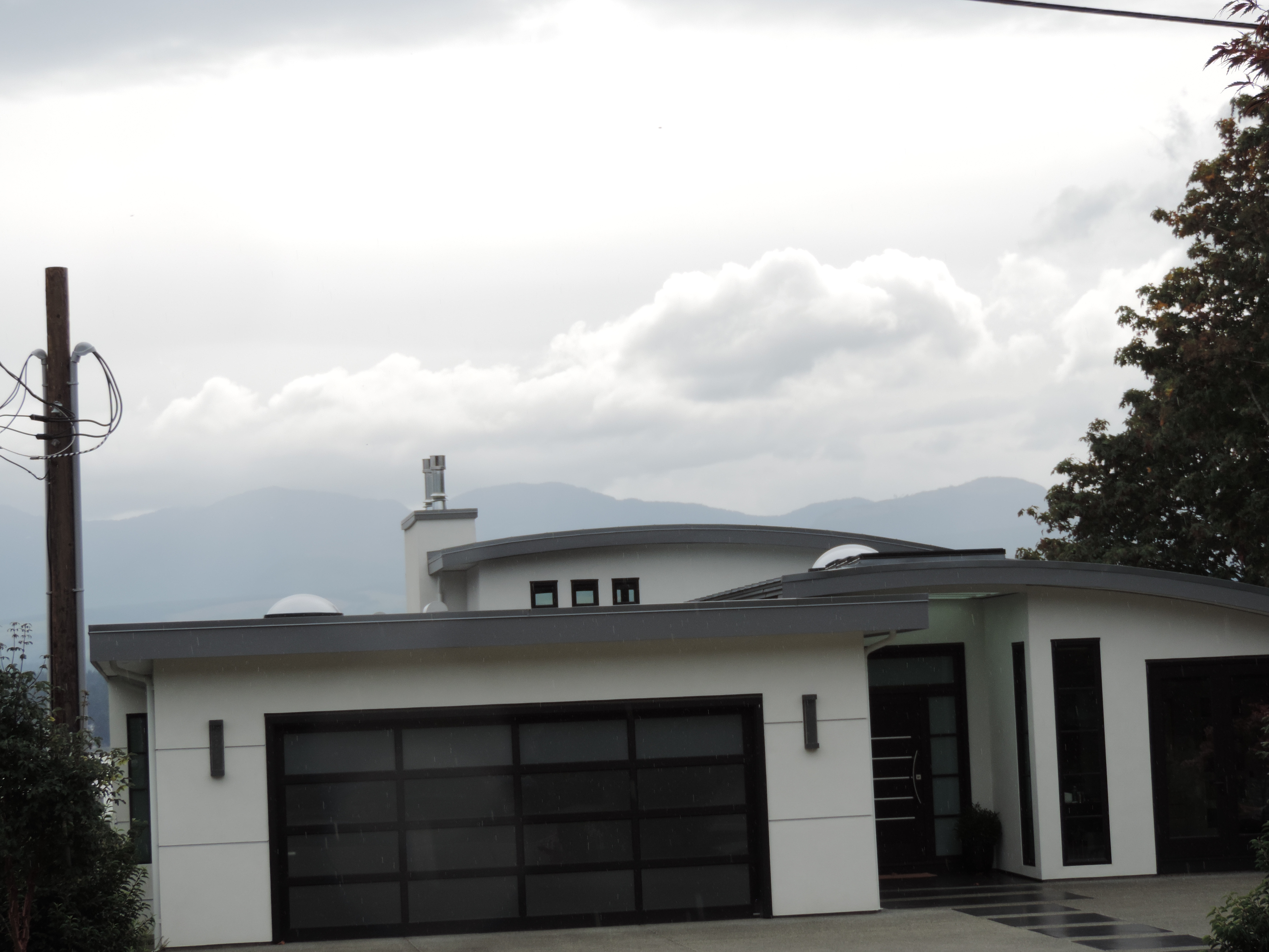 modern home with smooth flat panel siding, dark trim, and a curved metal roof edge