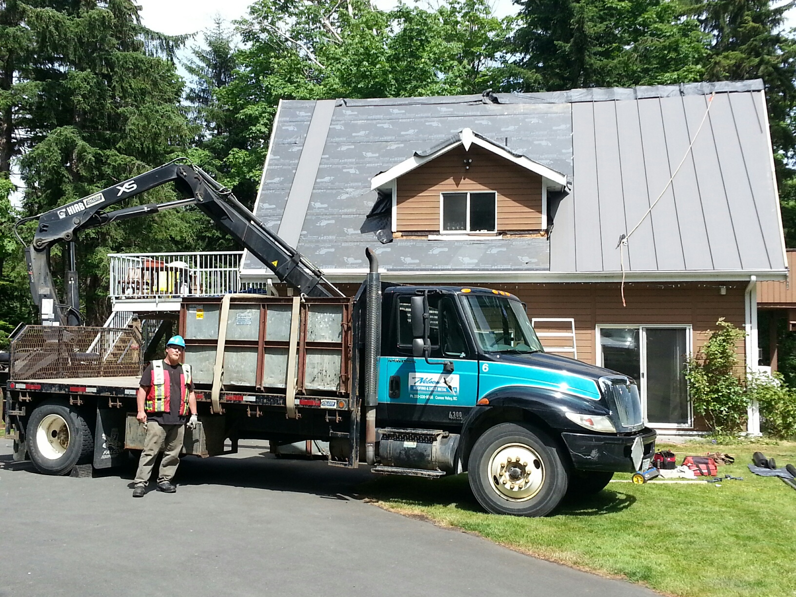 boom truck parked beside a house with new standing seam metal roof panels