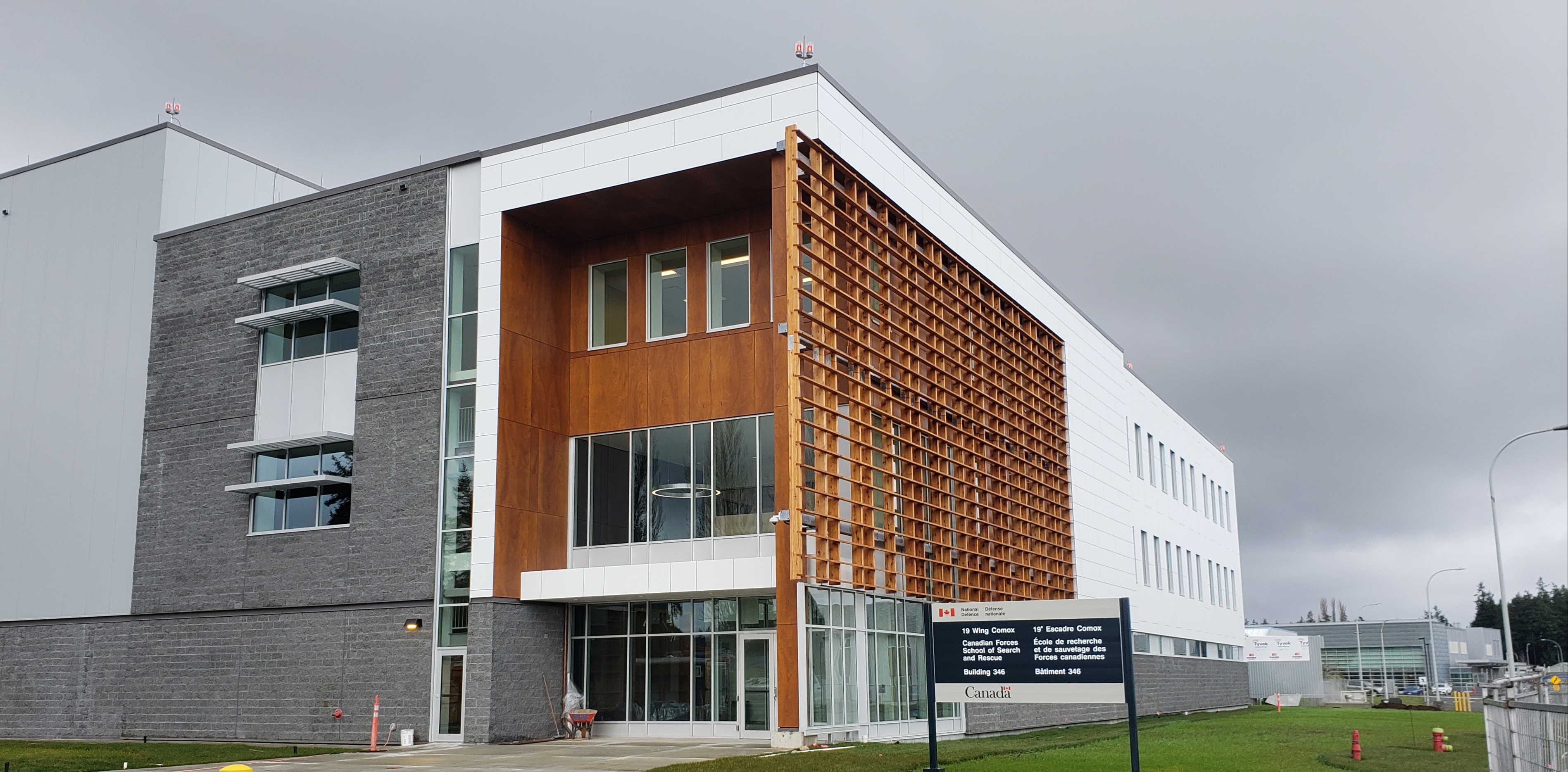commercial building exterior with metal panel cladding, brick base, and a timber slat sunscreen facade