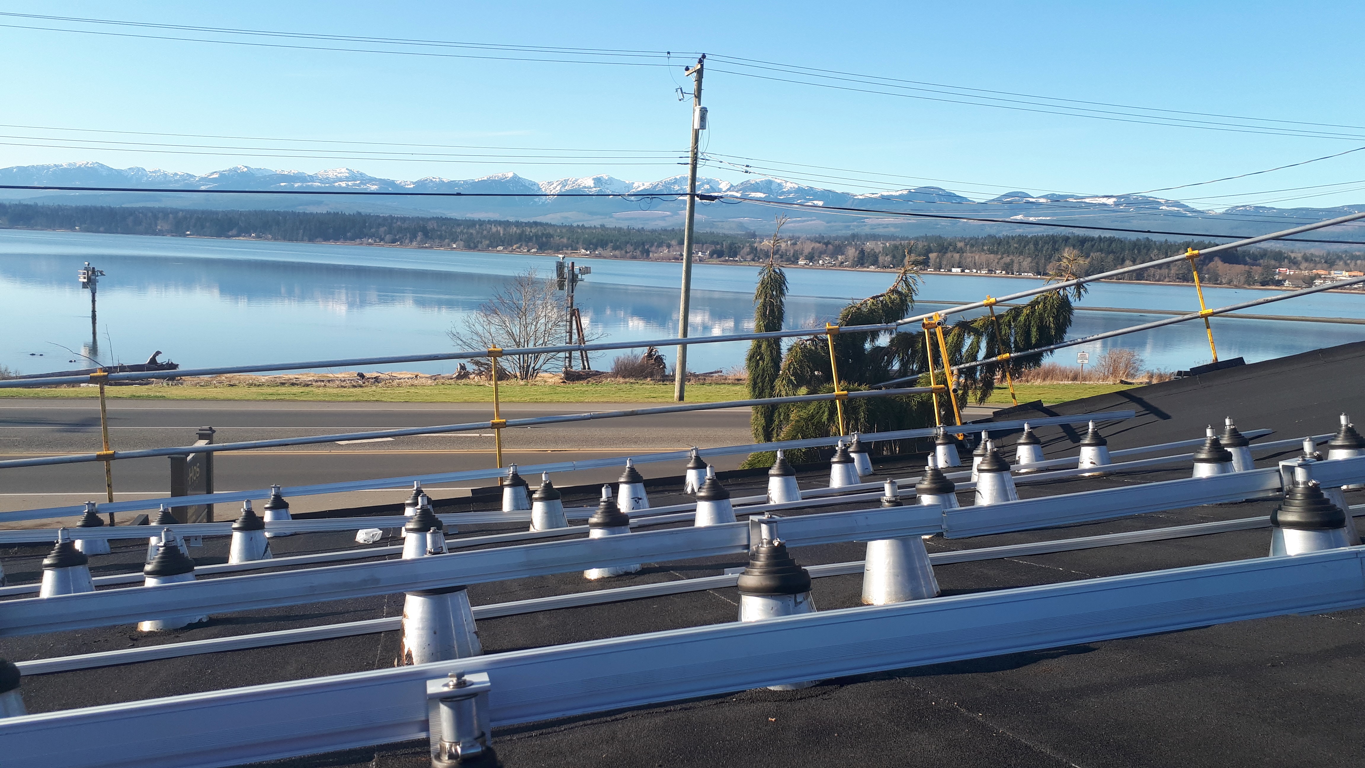 rooftop equipment mounting rails on a flat membrane roof overlooking water and mountains