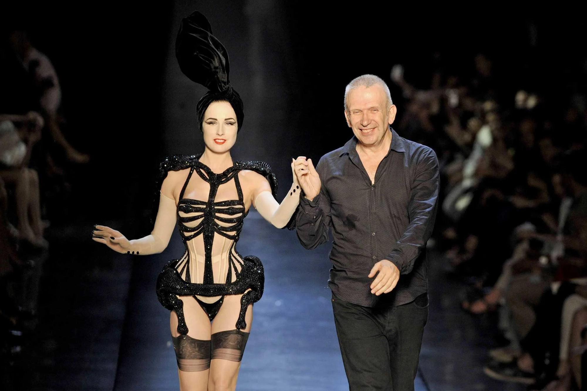 A fashion designer and fashion model walk the runway