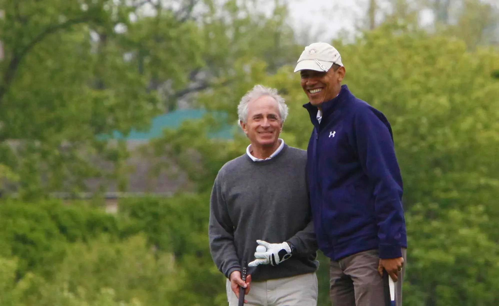 A golfer stands next to President Obama on a course