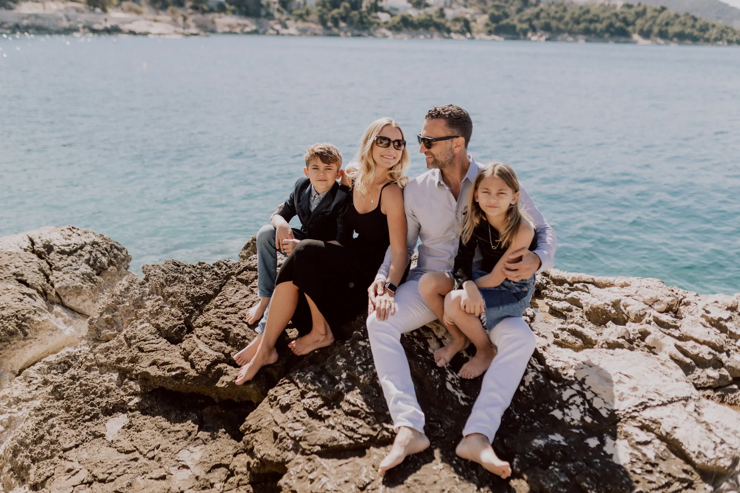 The Lockwood family sitting together on a rocky shore in Croatia