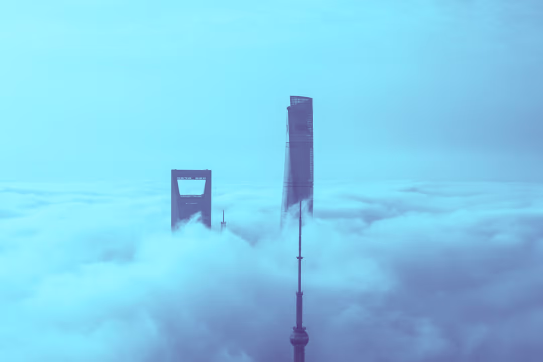 photo of the top of high-rise buildings appearing through clouds