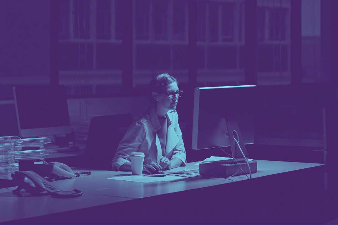 photo of a person working in front of a computer in a dimly lit room at night