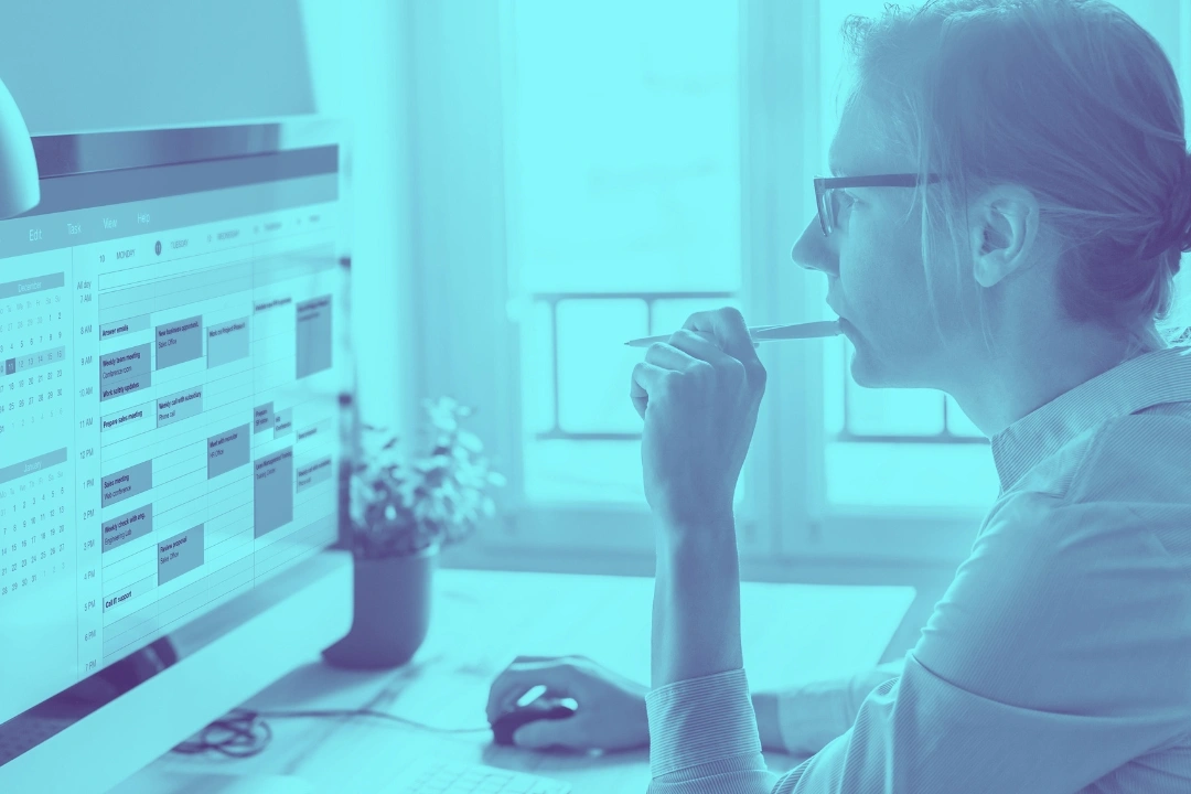 photo of a woman looking at a computer screen showing a calendar with several appointments