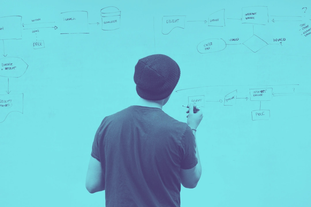 photo of a young man looking at a whiteboard containing diagrams