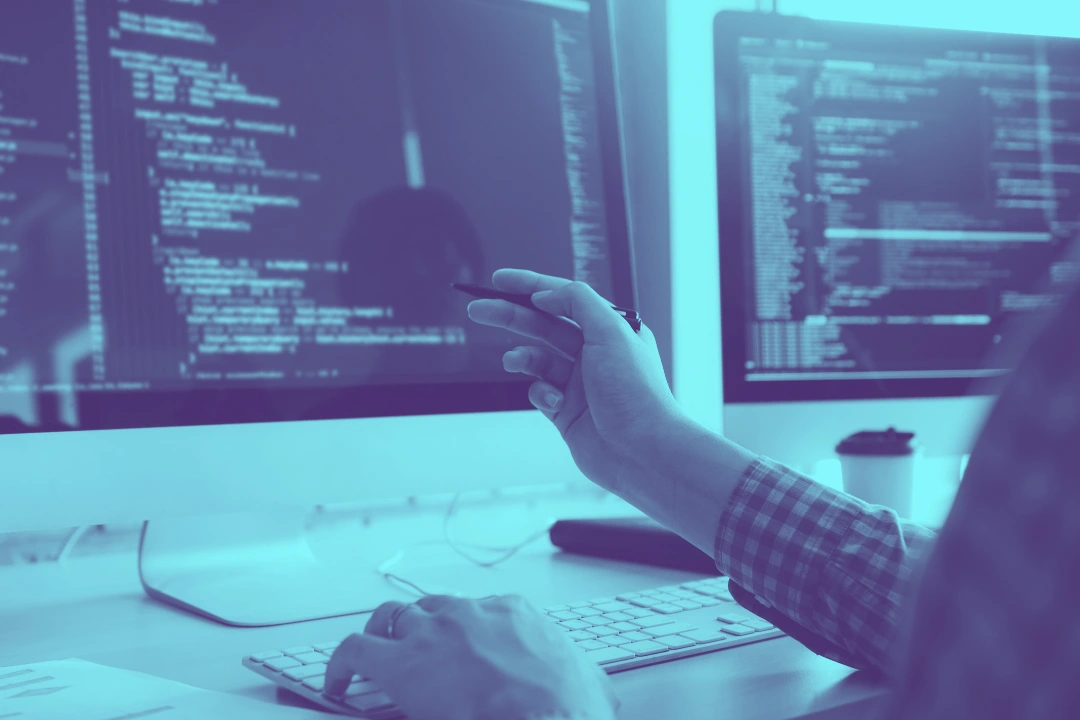 photo of a quality assurance engineer pointing at a computer screen showing code