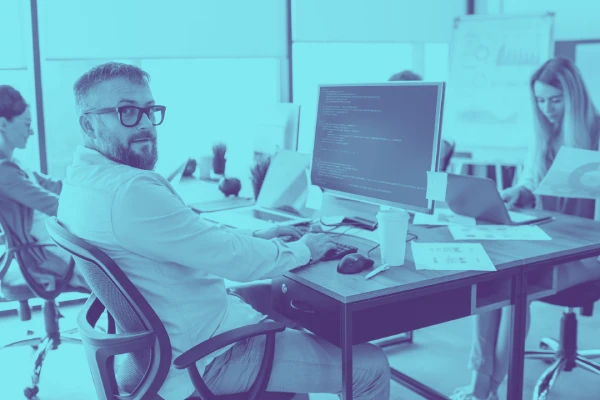 photo of a software engineer sitting at his desk and looking over his shoulders