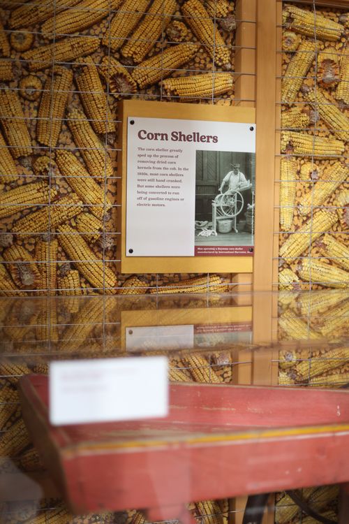 Museum display about corn shellers with an image of a man operating a hand-cranked corn sheller.