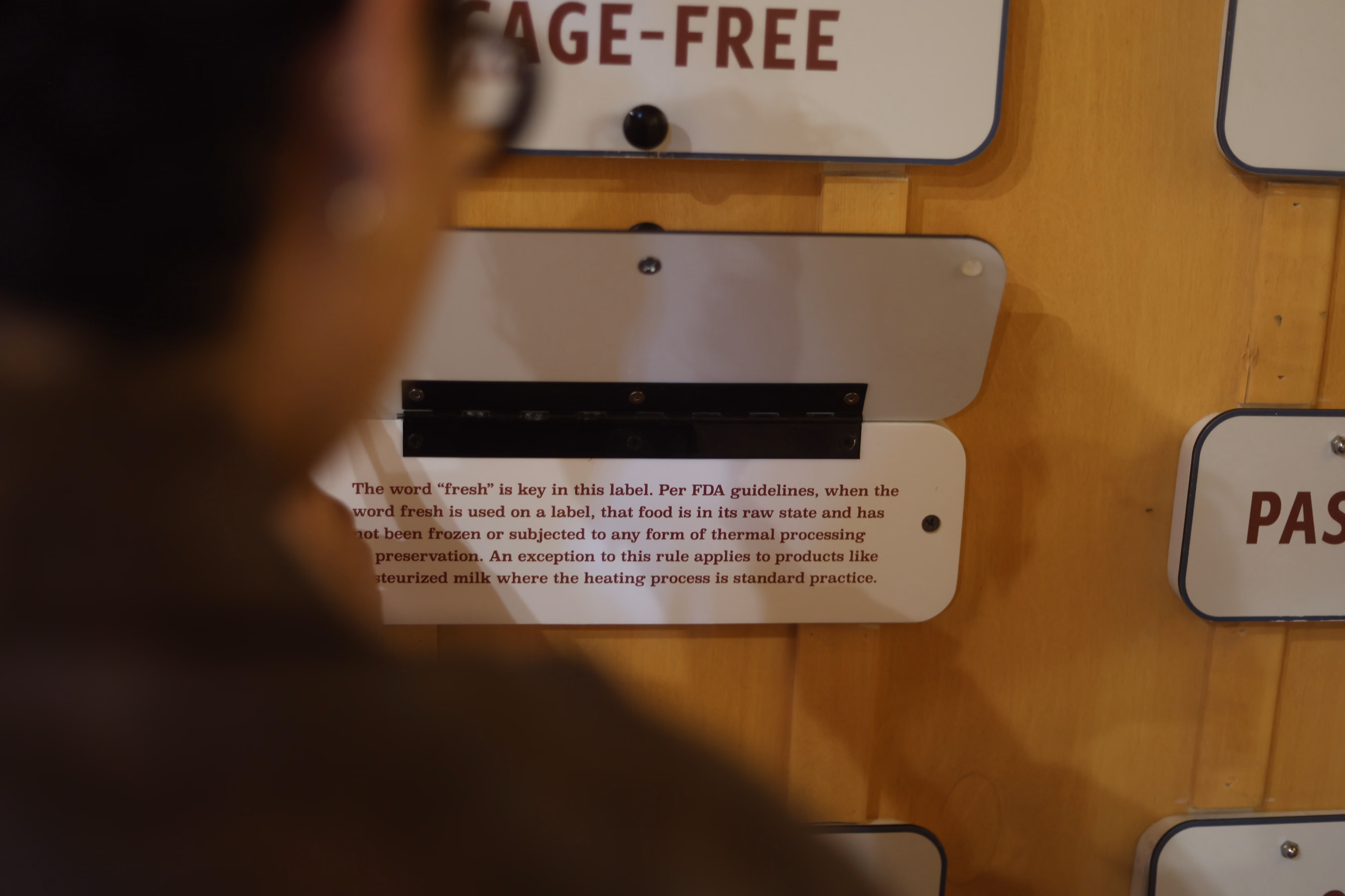 Person reading a sign explaining FDA guidelines for the word fresh on food labels.