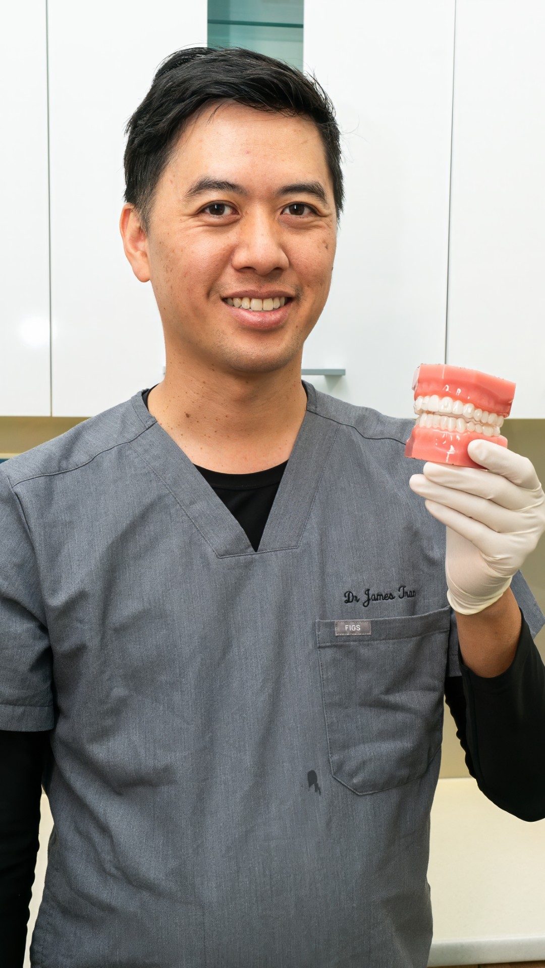 Dr James Tran holding dental implant model demonstrating tooth replacement options
