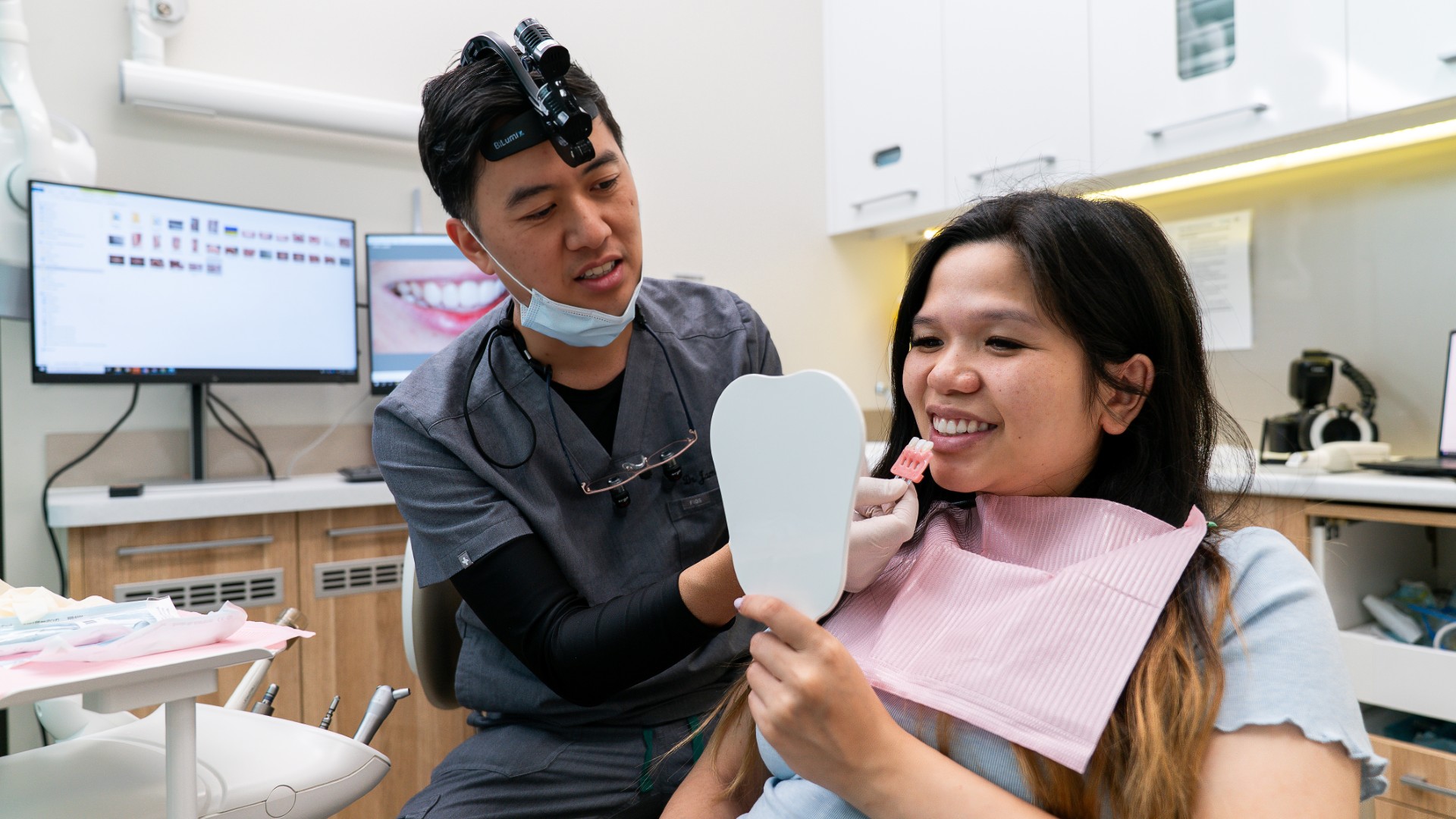 Patient viewing smile transformation in mirror after cosmetic dentistry