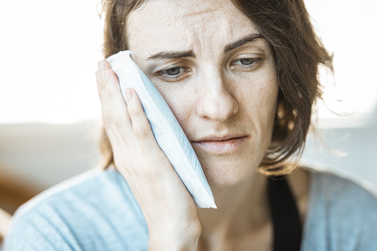 Person icing their jaw during the wisdom teeth removal recovery timeline