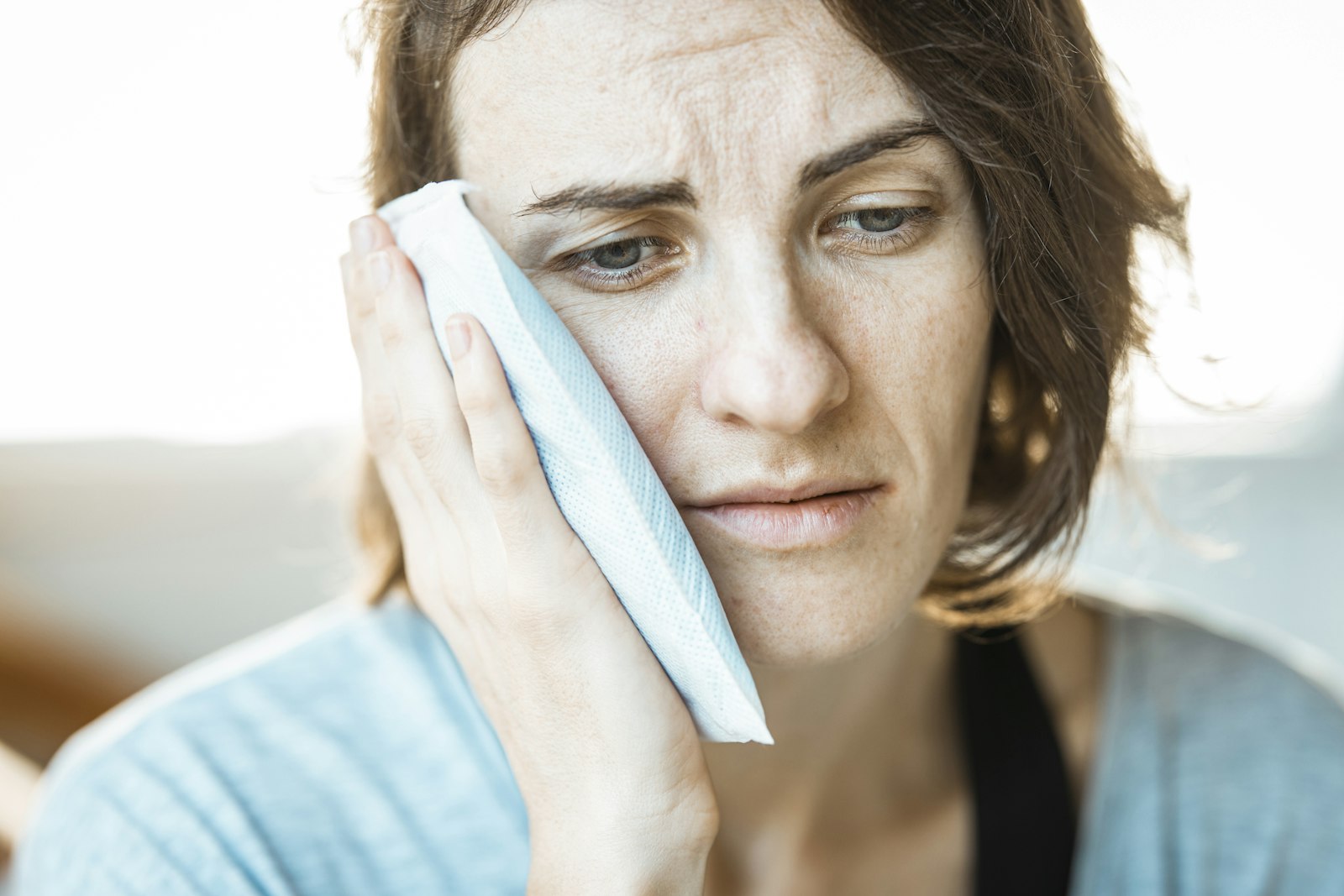 Person applying a cold compress to the cheek