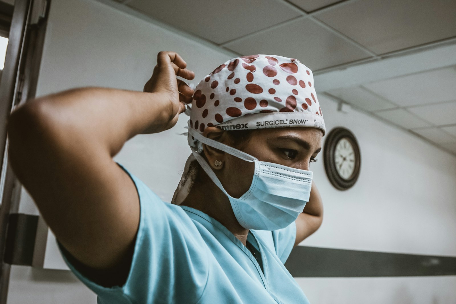 Healthcare worker in a teal top wearing a white face mask, illustrating how long masked shifts affect nurses' dental health