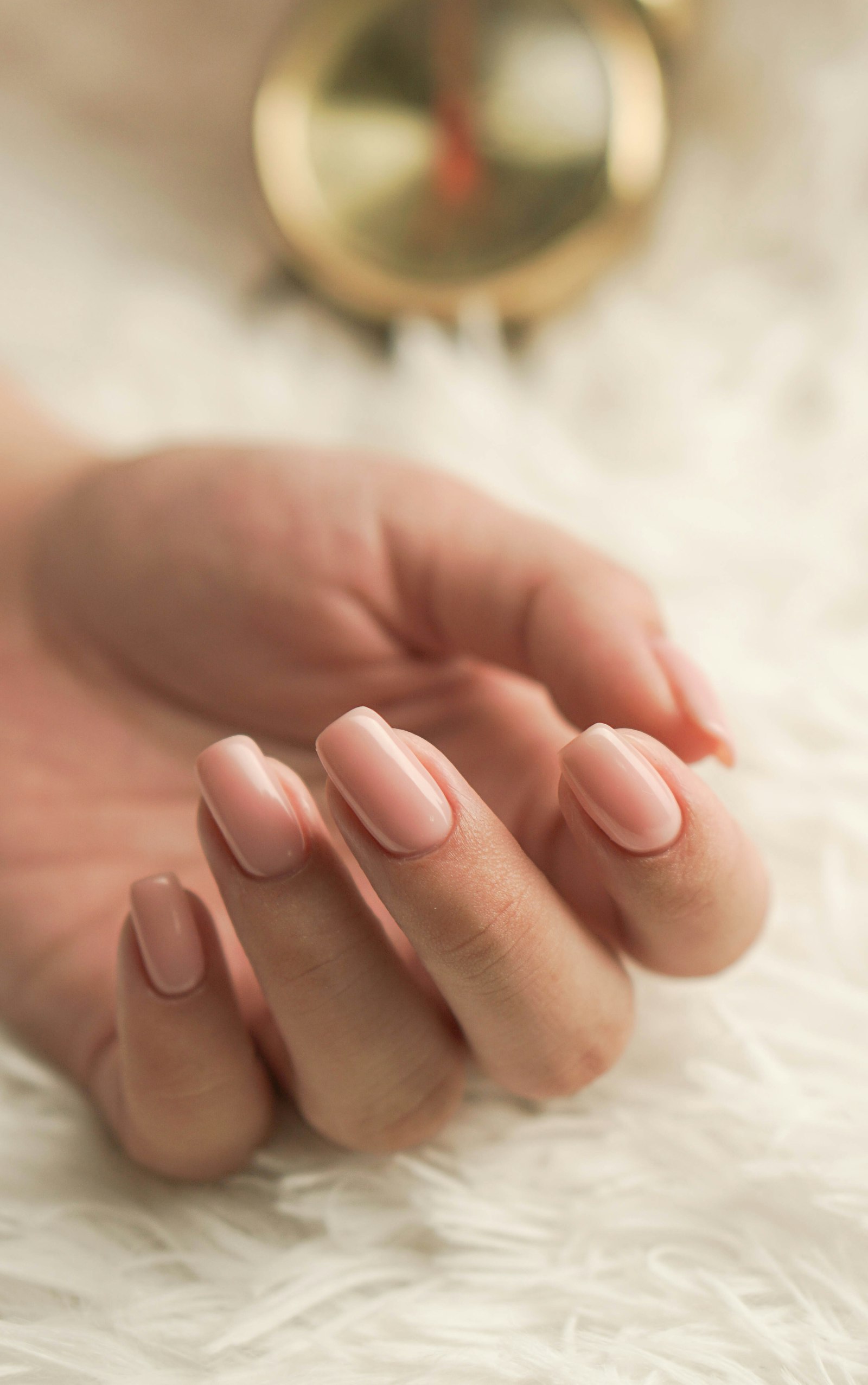 Well kept manicured hands resting on soft fabric, a reminder that beauticians dental health and hand care both benefit from a daily routine