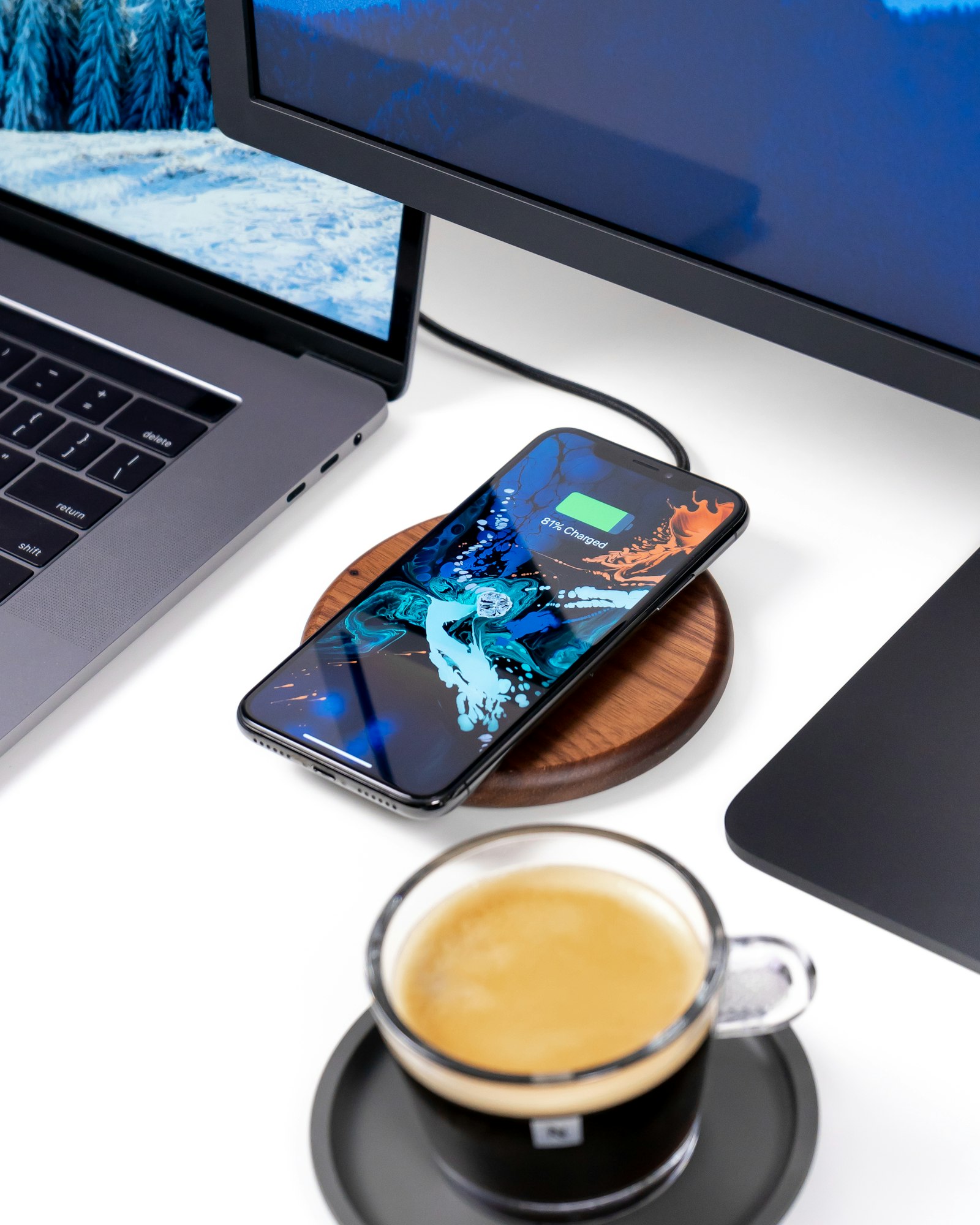 A clear glass cup of tea on a desk beside a phone and laptop, a simple desk-side habit for office dental health
