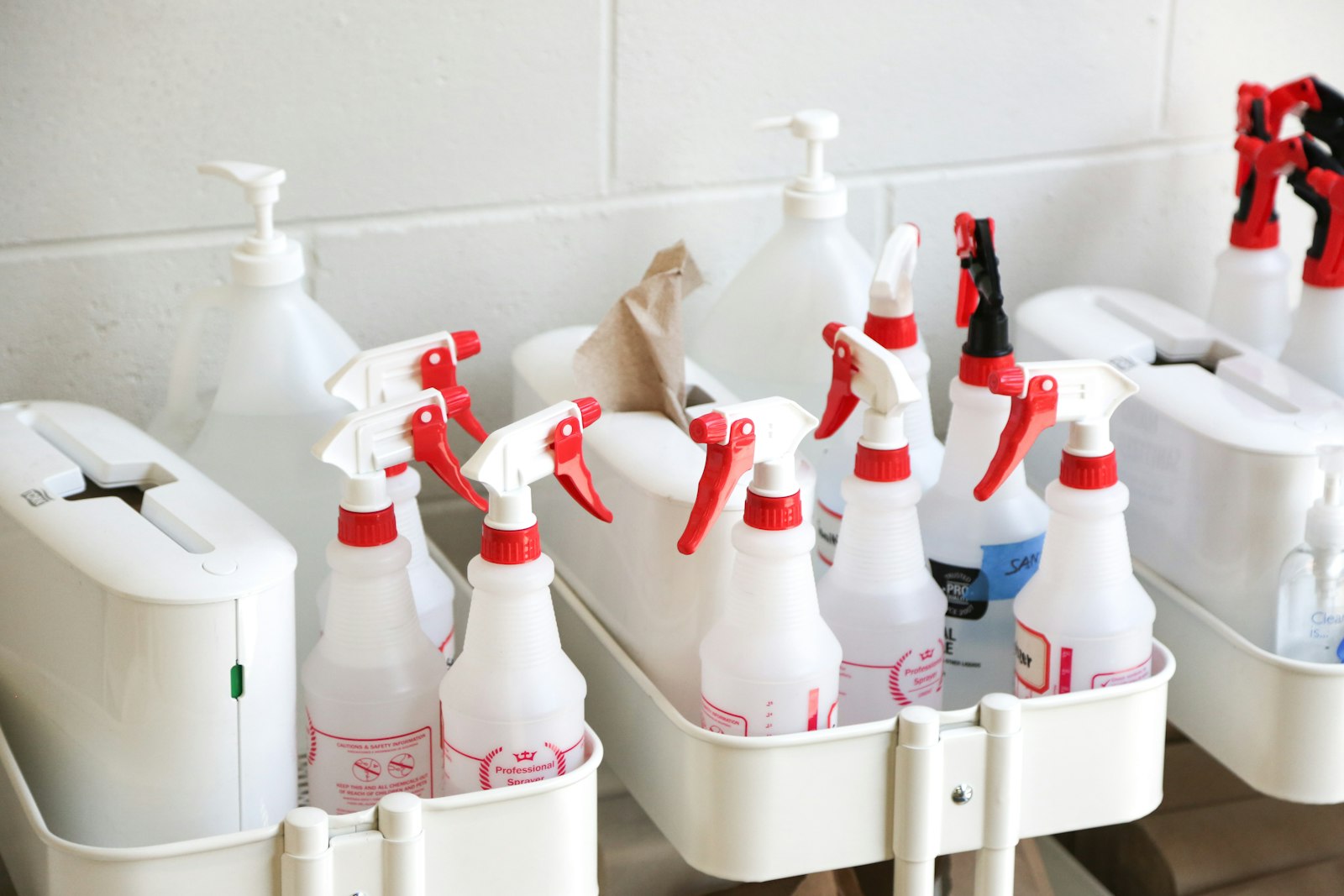White plastic cleaning bottles on a shelf, representing everyday product handling and dry mouth risks for commercial cleaners