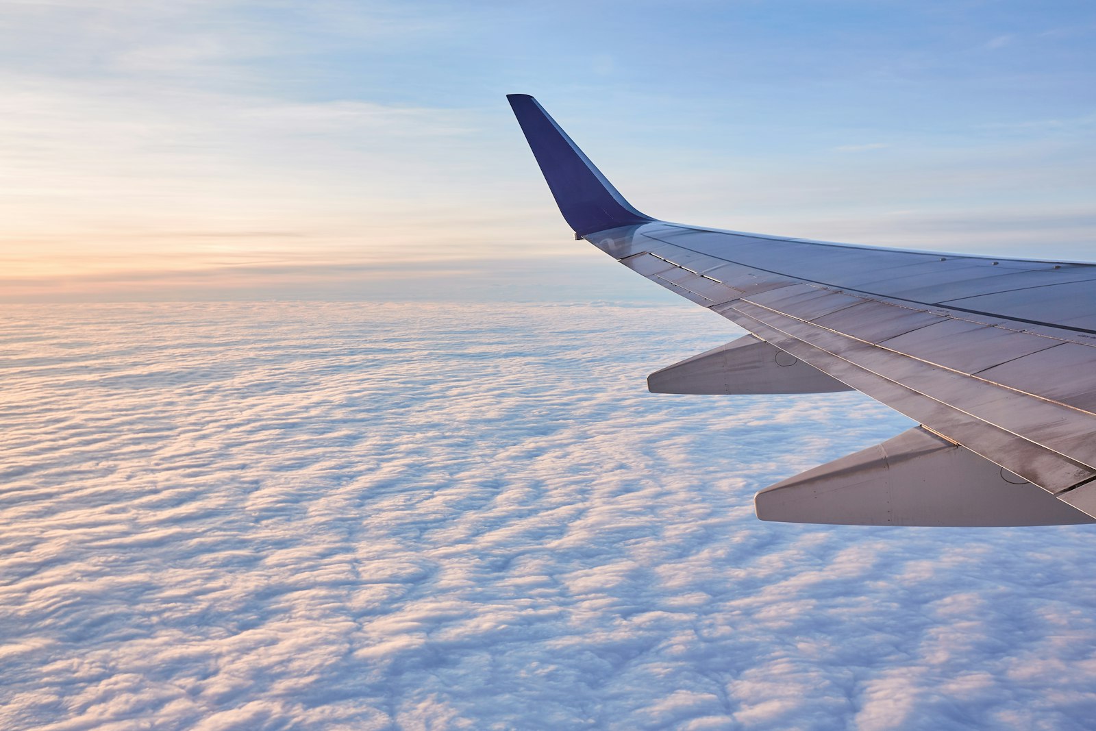 Aeroplane wing above white clouds in daylight, a reminder that dental health for pilots and cabin crew is affected by altitude