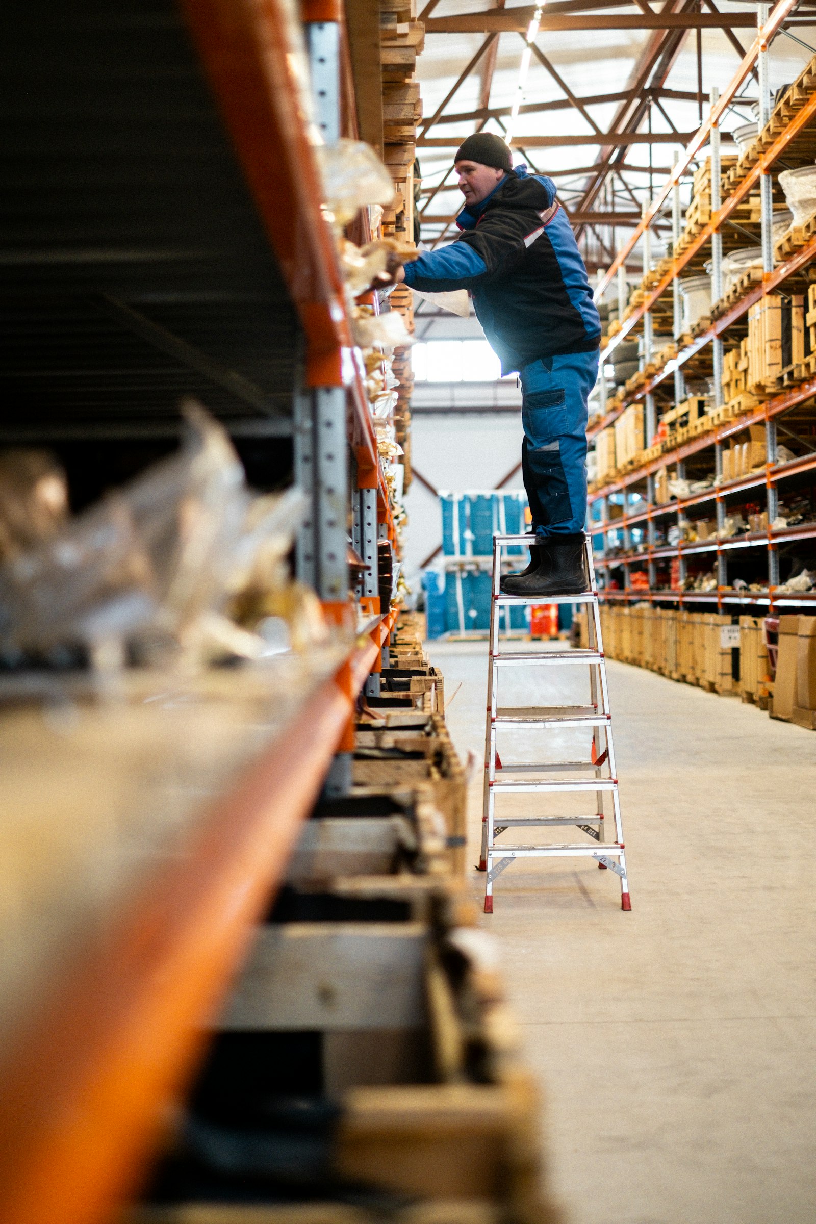 Warehouse worker on a ladder at storage shelving, illustrating warehouse worker dental health on the job