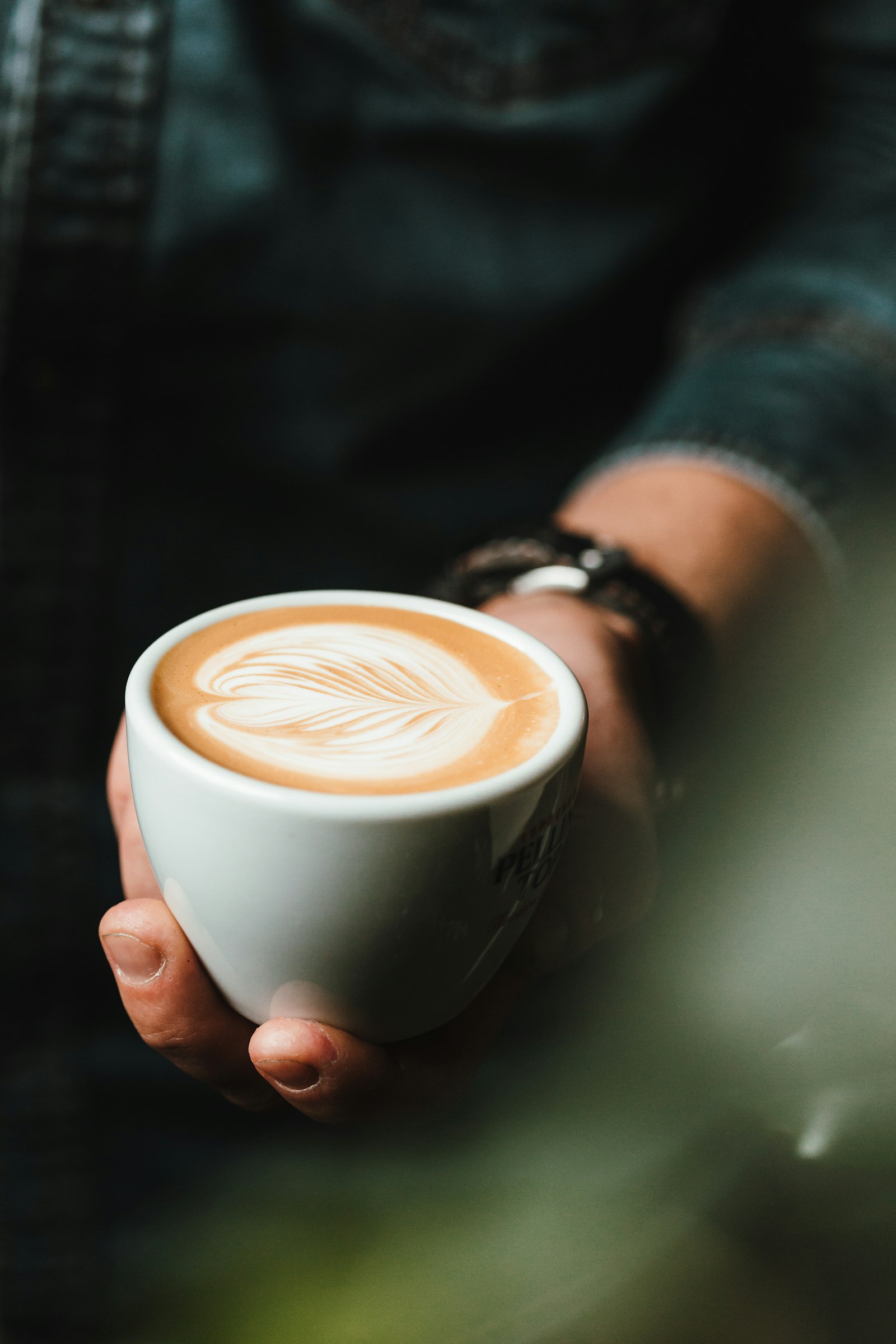 Person holding a cup of cappuccino, a reminder that timing matters for baristas coffee dental health