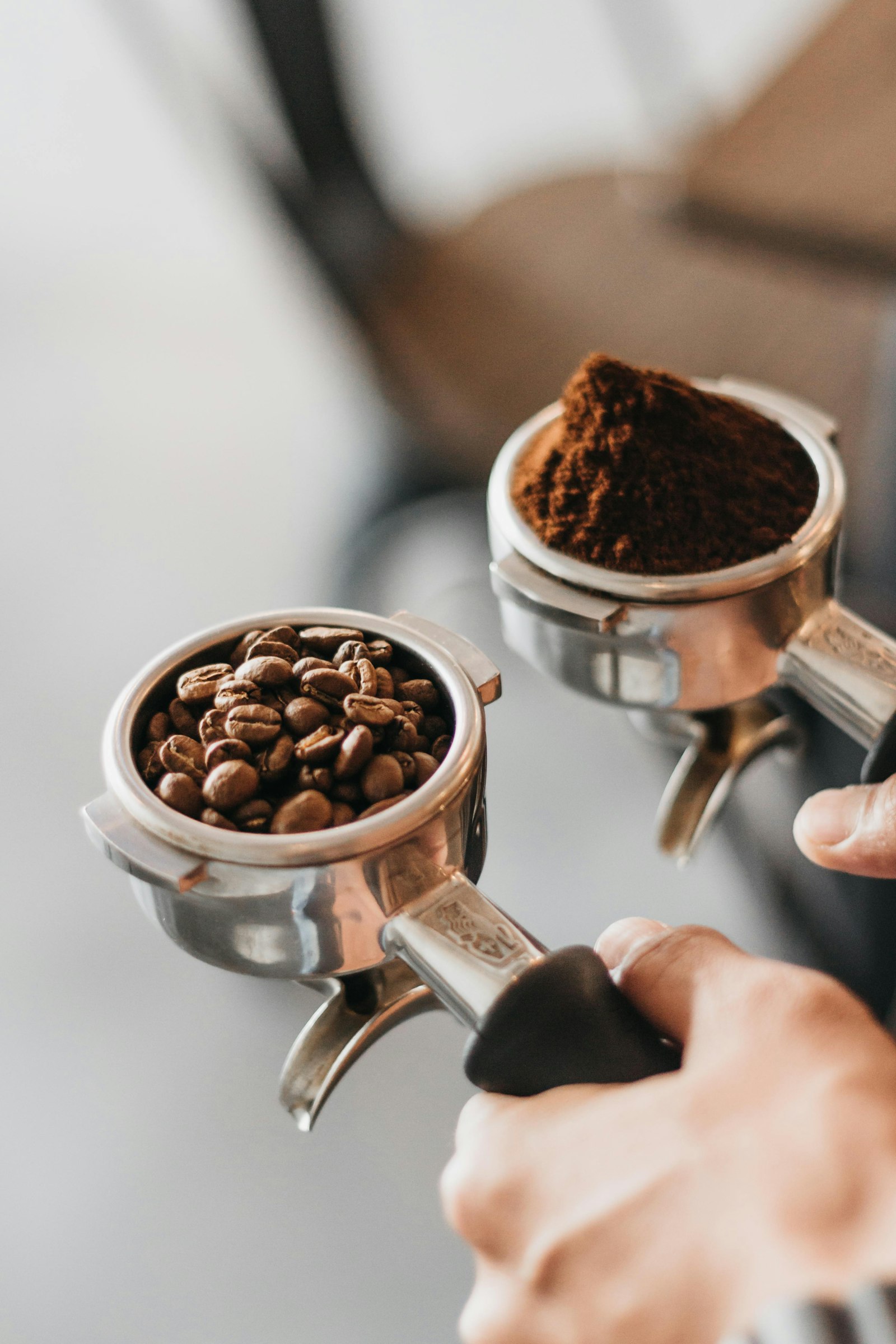 Hands holding two portafilters of ground coffee, showing the tasting routine behind baristas coffee dental health
