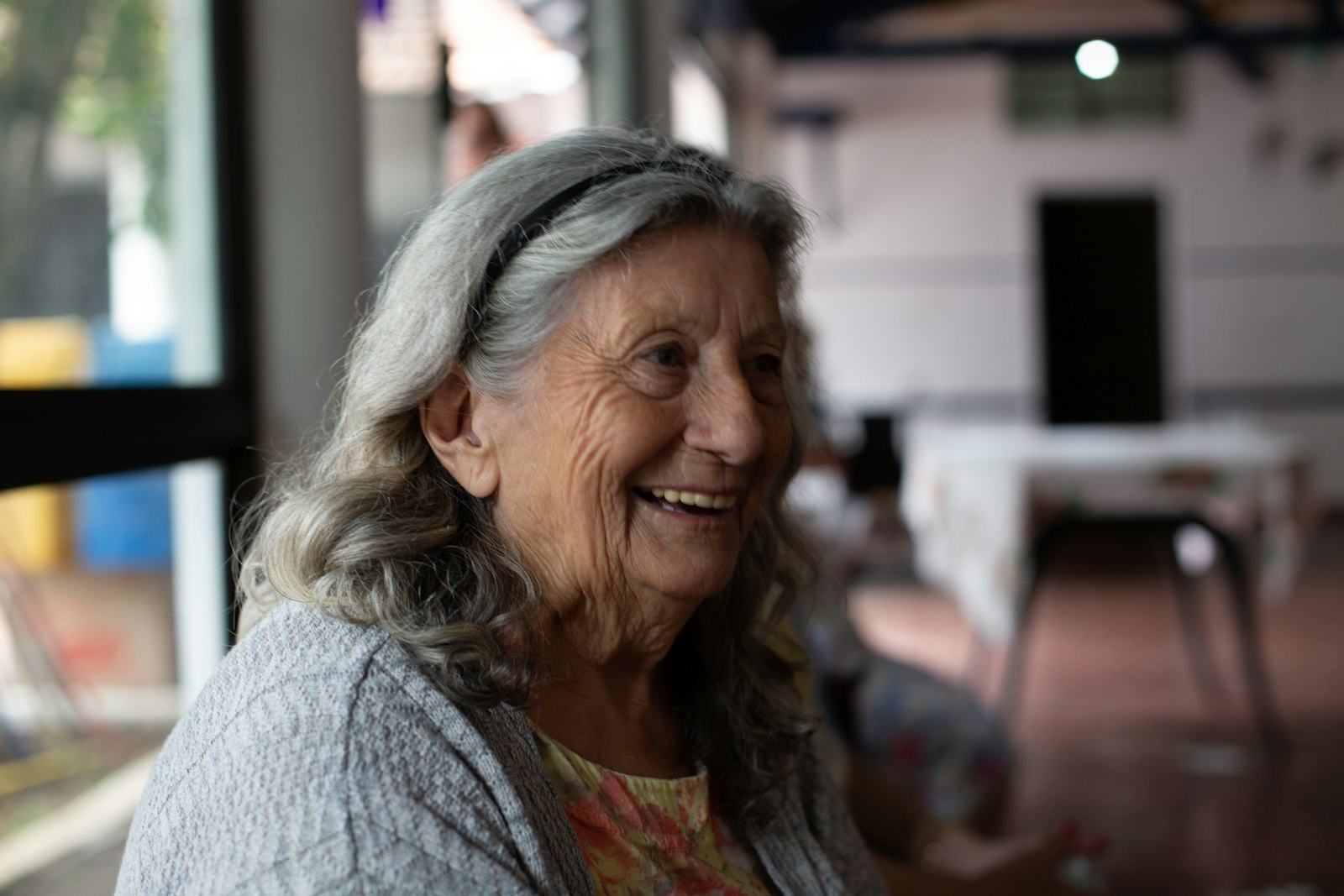 Baking soda for teeth: older woman smiling broadly in a warm cafe