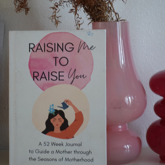 Book cover titled 'Raising Me To Raise You' with an illustration of a woman watering a flower on her head, placed next to a pink vase and a red object.
