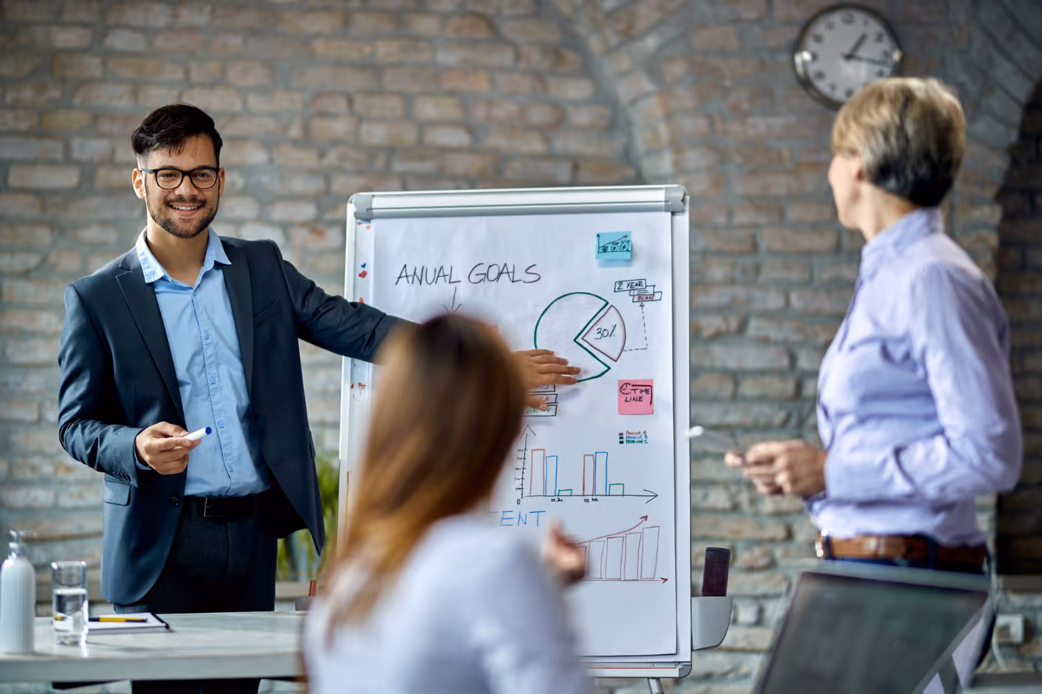 An image showing a man pointing at a whiteboard in a meeting