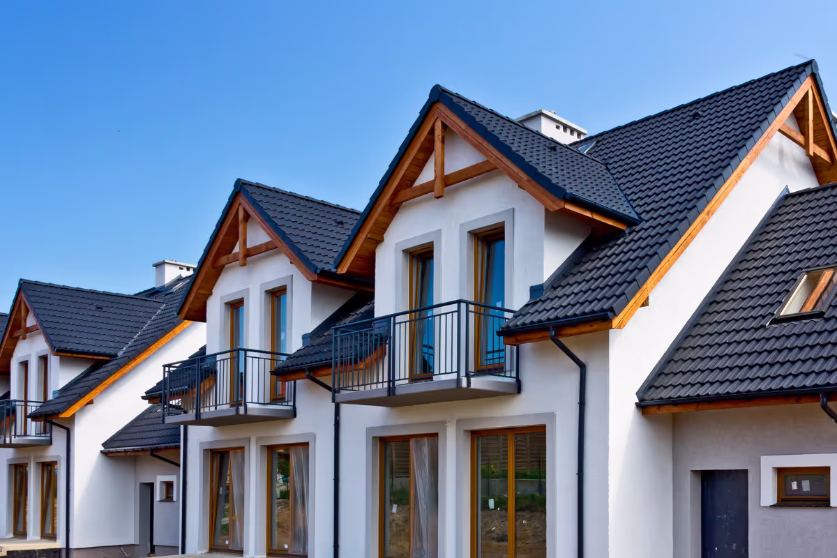 A series of houses lined up, each adorned with black roofs, creating a cohesive and striking neighborhood appearance