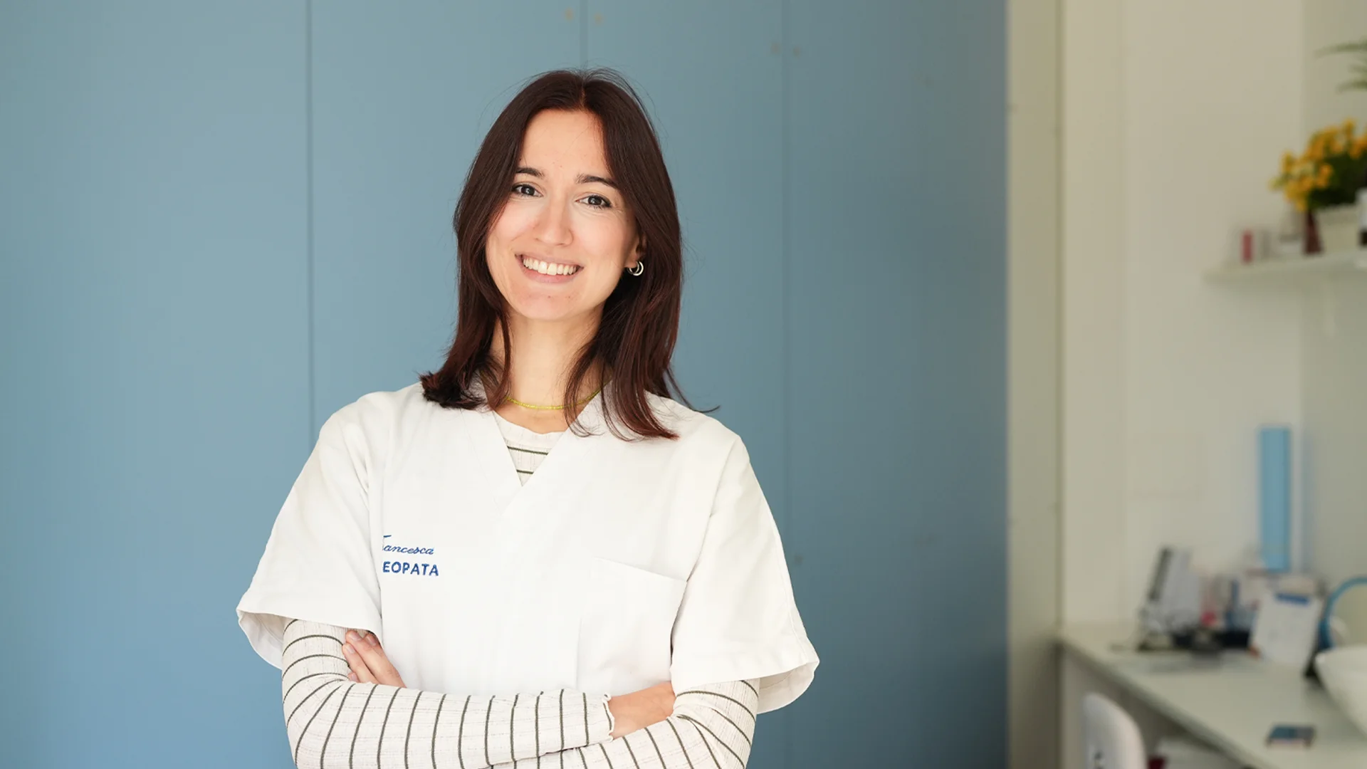 Ritratto dell'osteopata Francesca Trivini Bellini in camice bianco all'interno del suo studio medico.