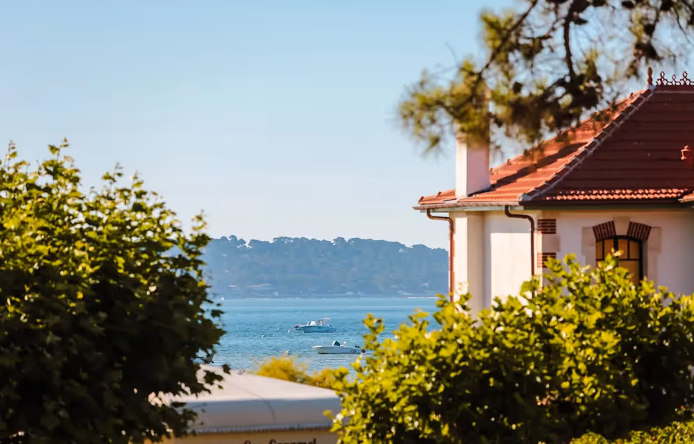 Glimpse of the Arcachon Bay between rooftops and greenery from the Cap Ferret Prestige Suite
