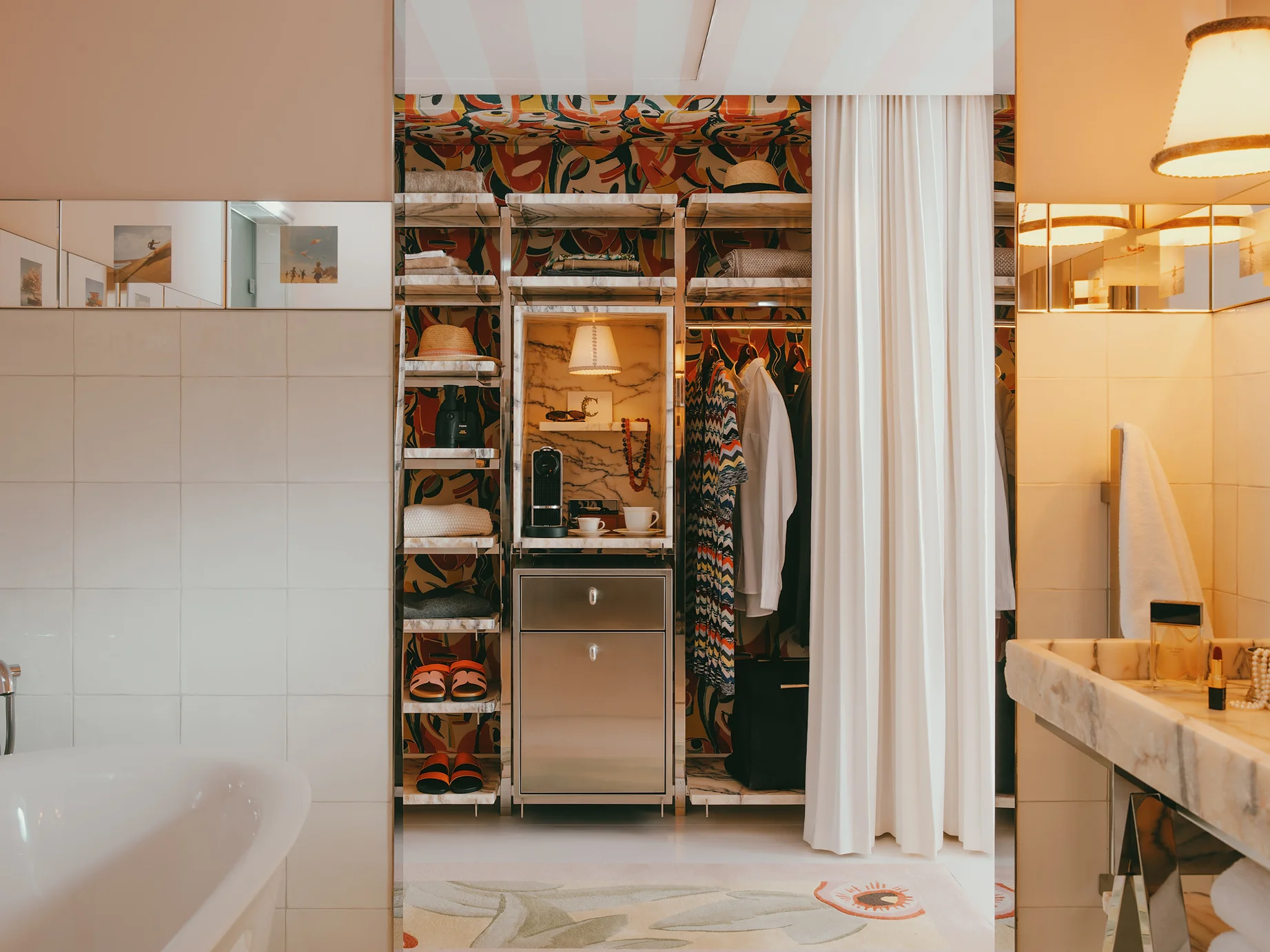 Dressing ouvert de la Villa Colette avec étagères en marbre, papier peint graphique coloré, machine à café et vêtements suspendus