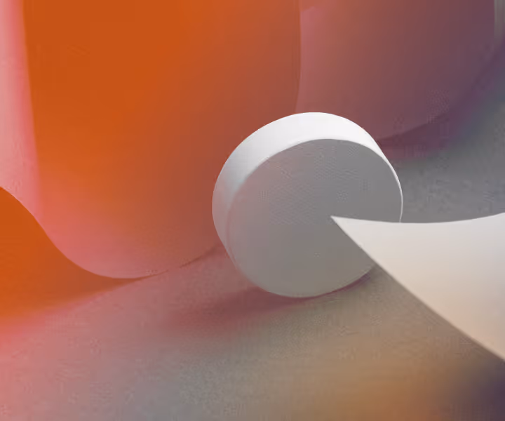 Close-up of a white round pill with a sharp-edged object pointing at it on a surface with warm lighting.