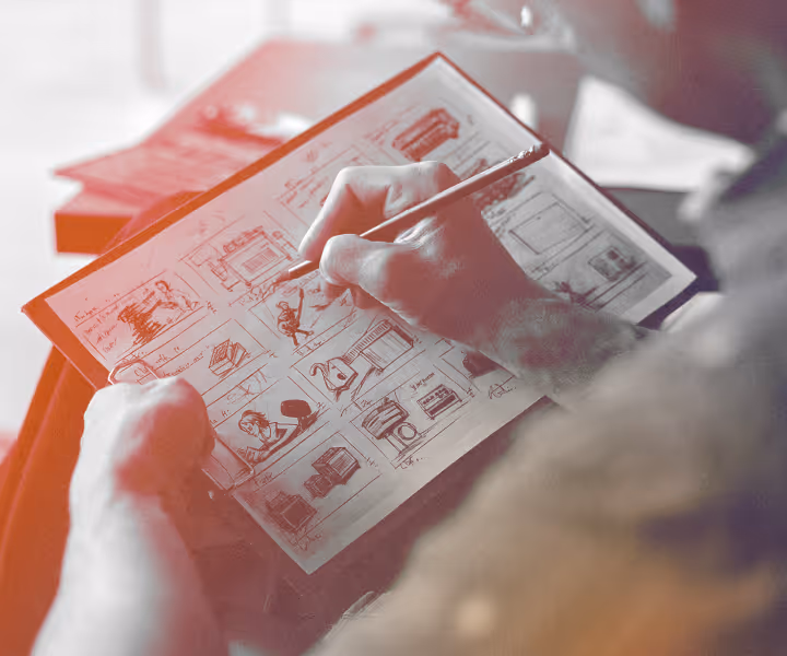 Person sketching storyboards with a pencil on paper showing multiple comic-style panels.