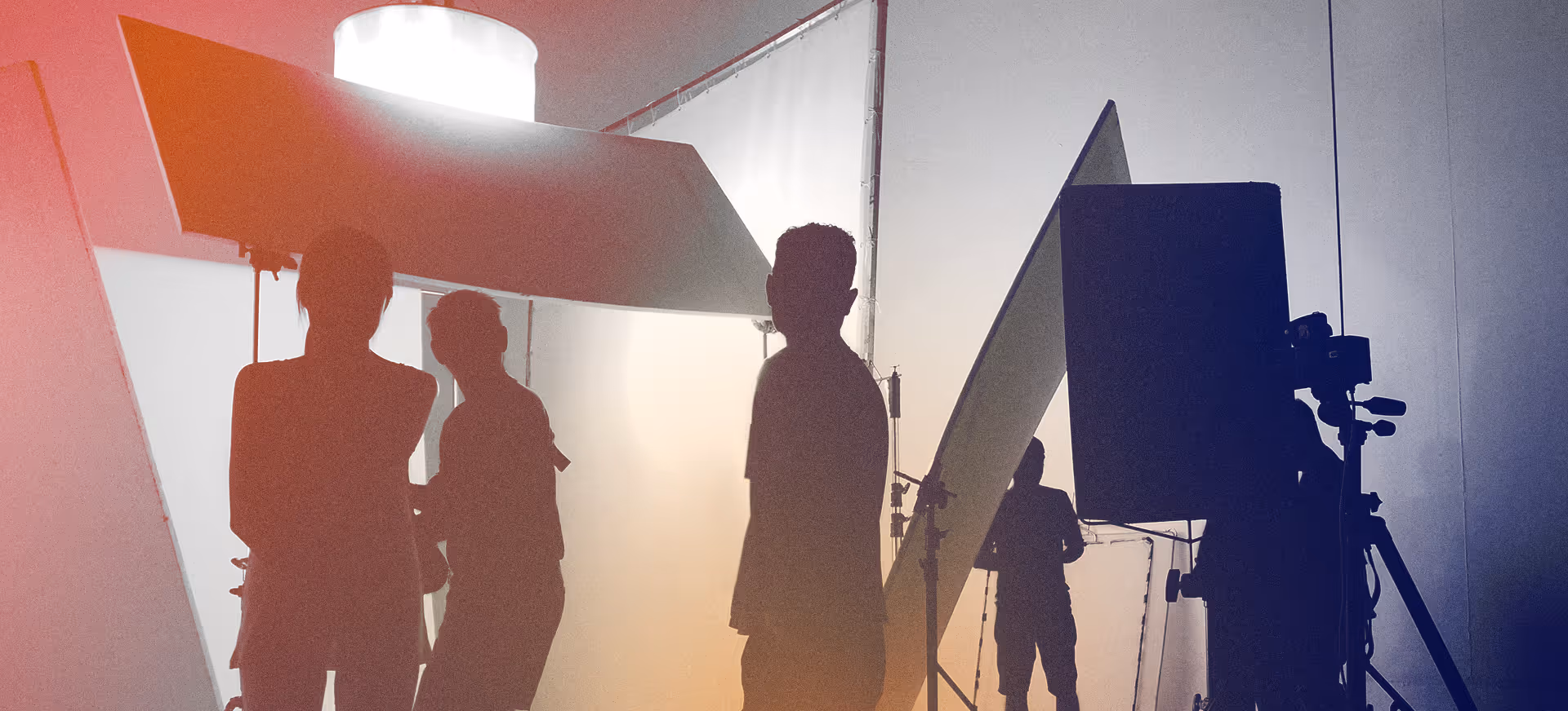 Silhouettes of people on a photo or video shoot with lighting and camera equipment in a studio.
