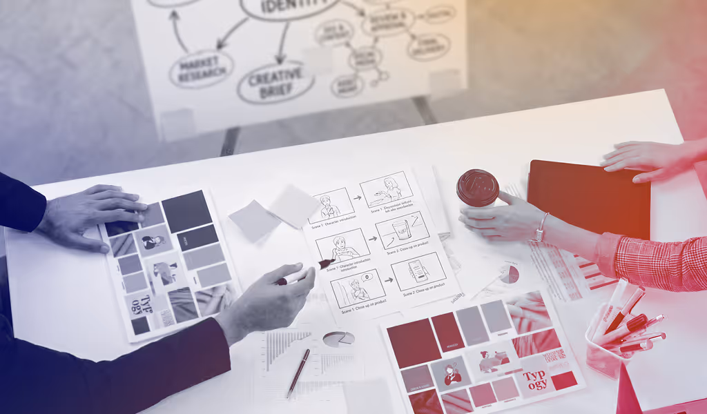 Two people reviewing color swatches, storyboards, and typography samples on a white table.