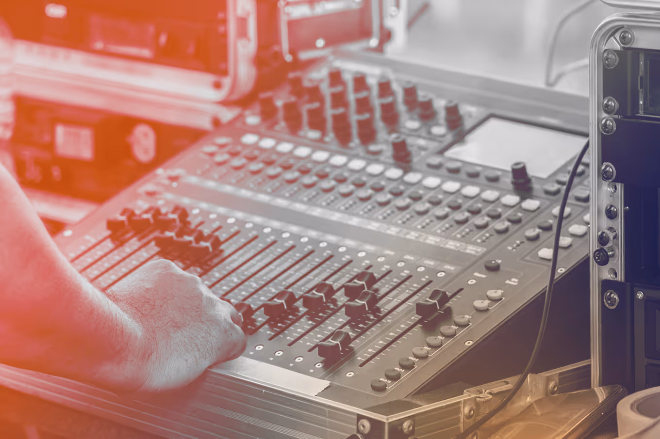 Hand adjusting sliders on a professional audio mixing console with multiple knobs and buttons.