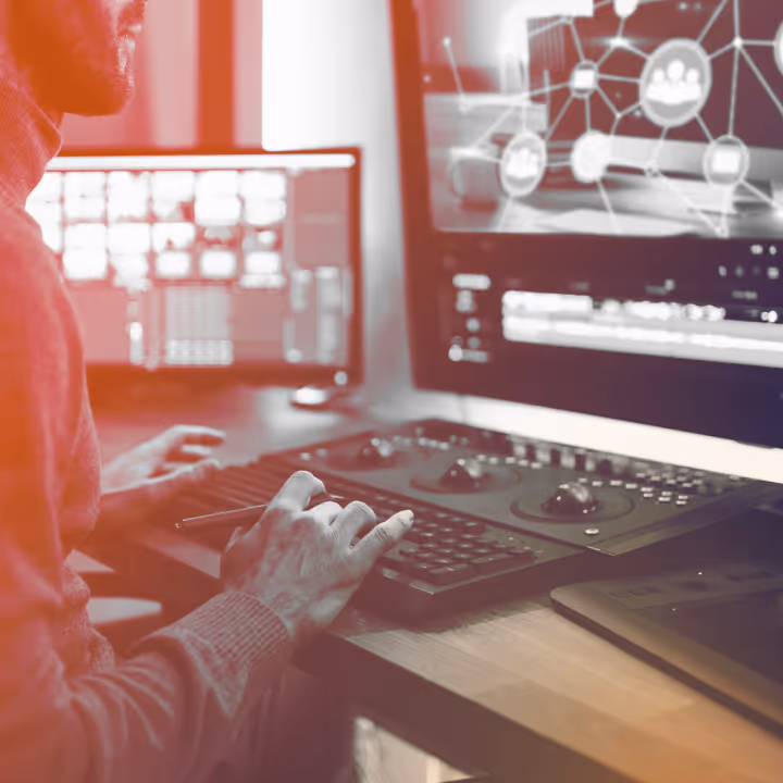 Person using a computer with dual monitors showing video editing and network graphics.