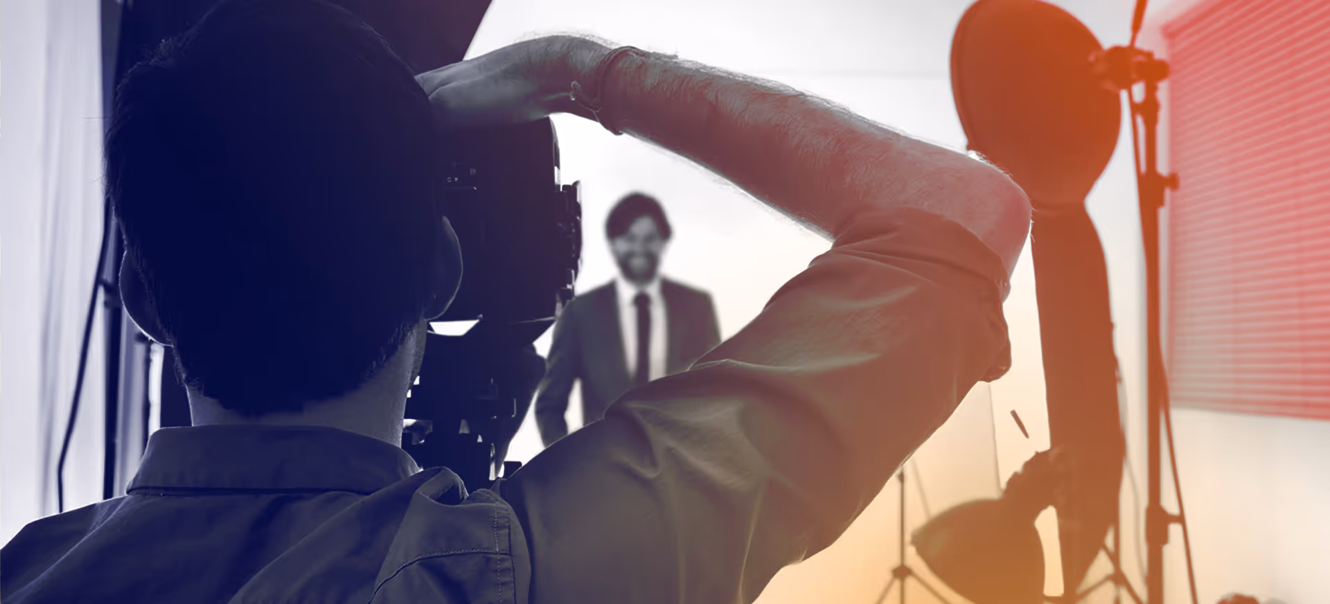 Photographer taking a photo of a man in a suit in a studio with lighting equipment.