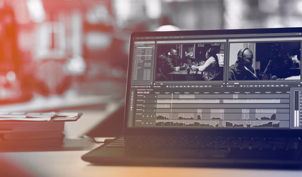 Laptop screen showing video editing software with black and white podcast footage on a desk with blurred background.