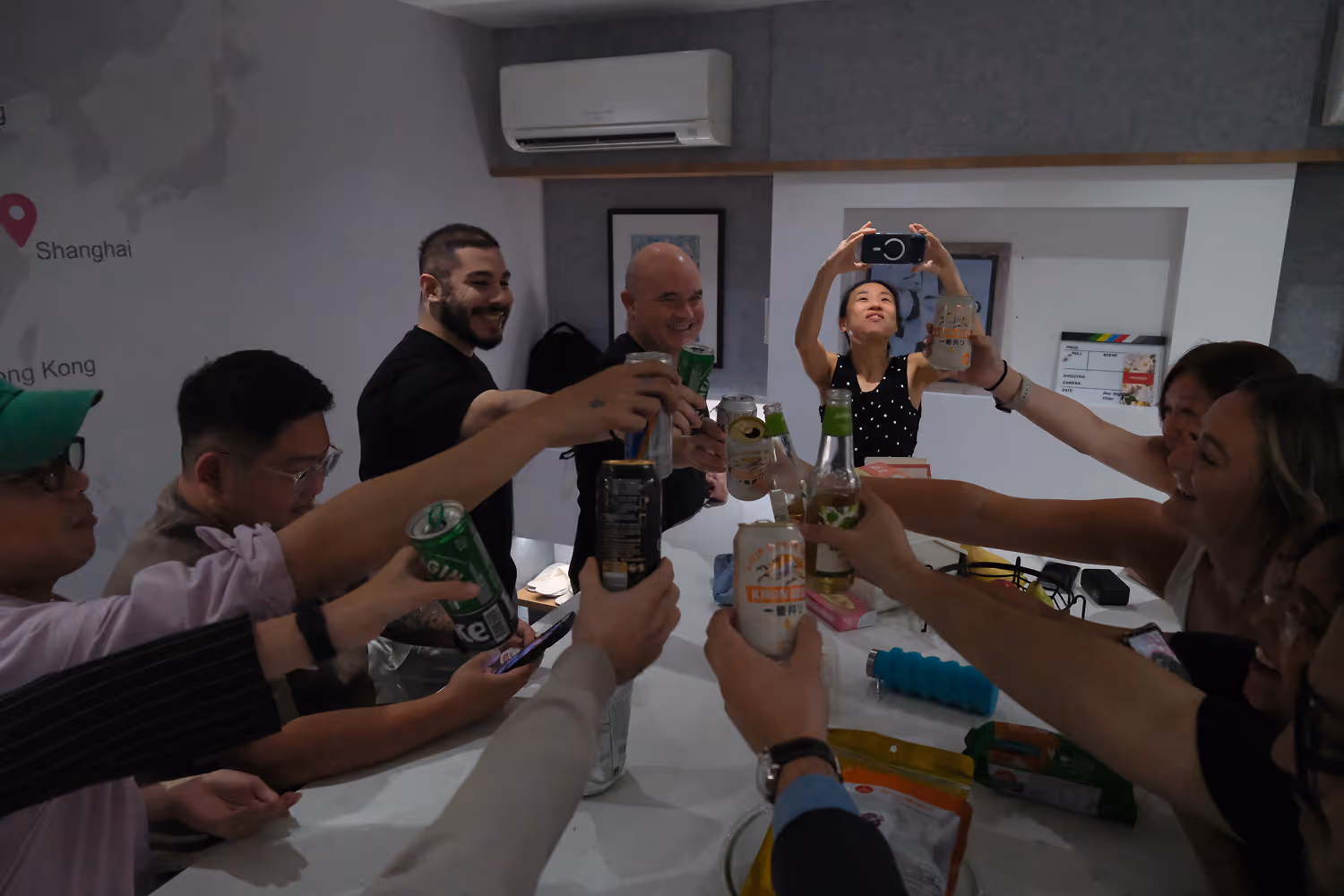Group of diverse people raising drinks together in a celebratory toast indoors.