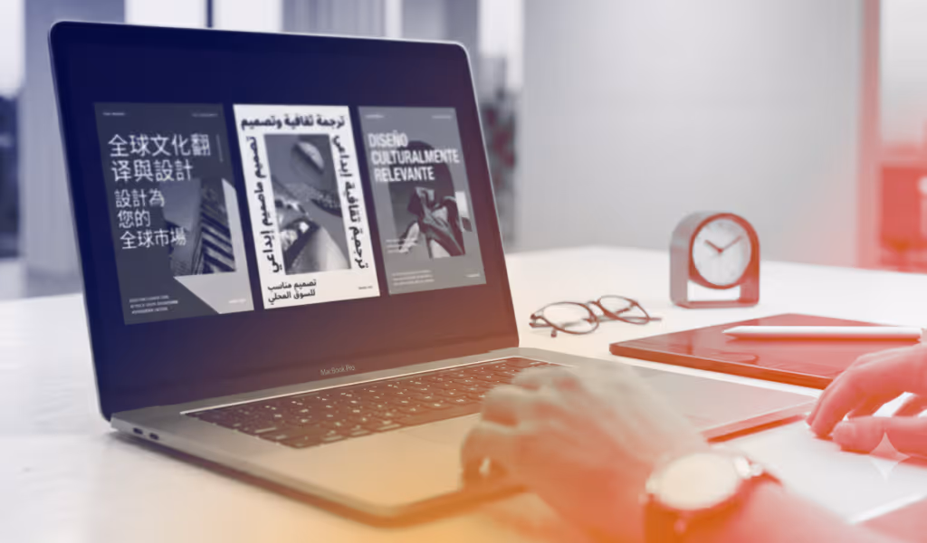 Person using a MacBook Pro displaying multilingual design content on a white desk with glasses and a clock.