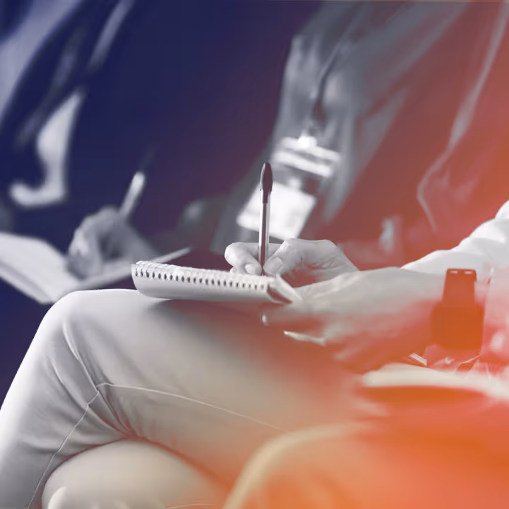 People sitting and writing notes in notebooks during an event or meeting.